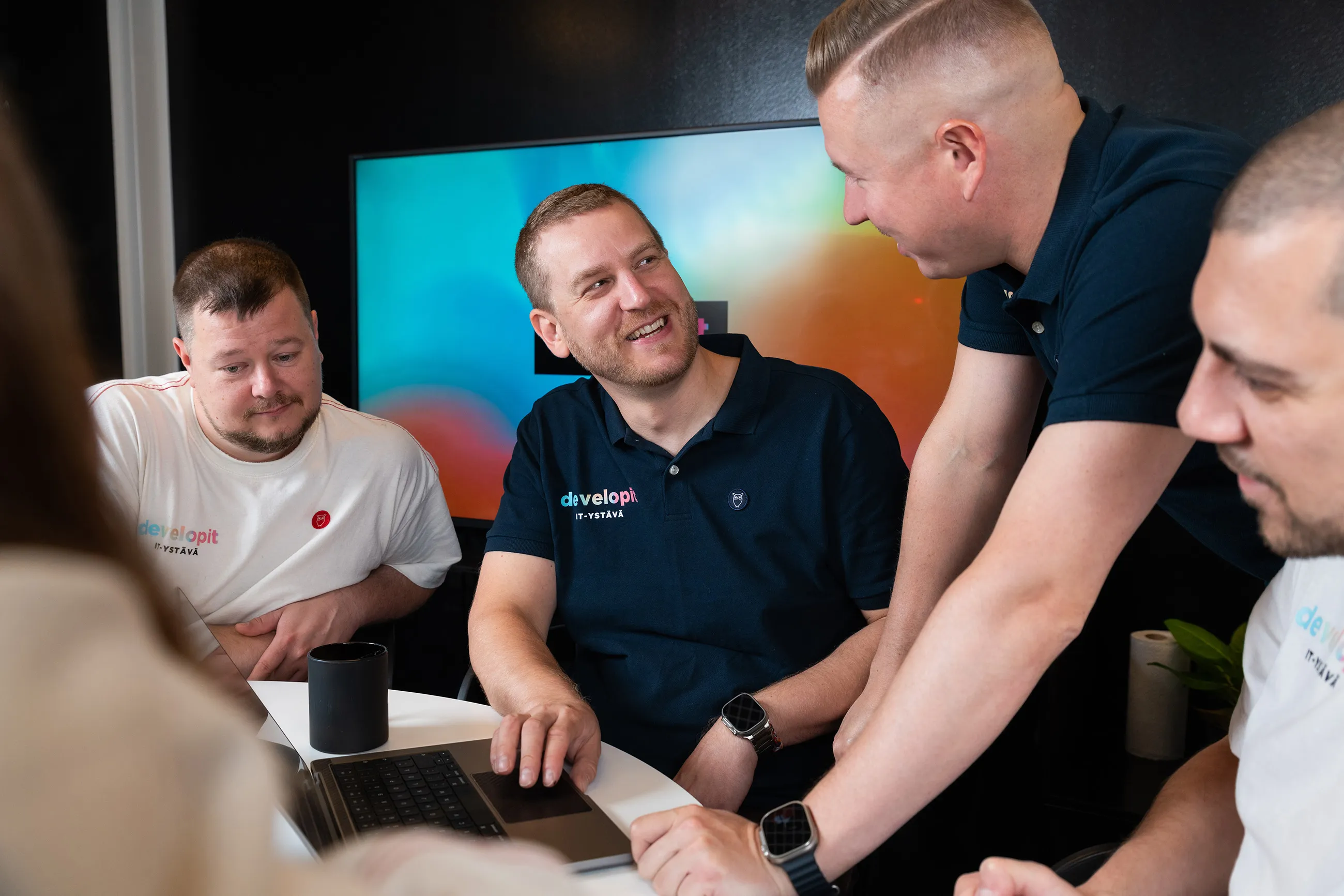 Developit team members having a cheerful conversation around a table.